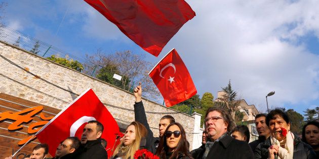 People wave Turkish flags during a gathering in front of the Reina nightclub, which was attacked by a gunman, in Istanbul, Turkey.