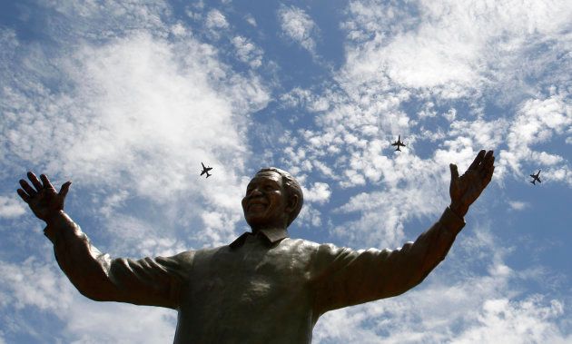 South African military jet fighters fly past a 9-metre (30-feet) bronze statue of the late former South African President Nelson Mandela after it was unveiled as part of the Day of Reconciliation Celebrations at the Union Buildings in Pretoria December 16, 2013.