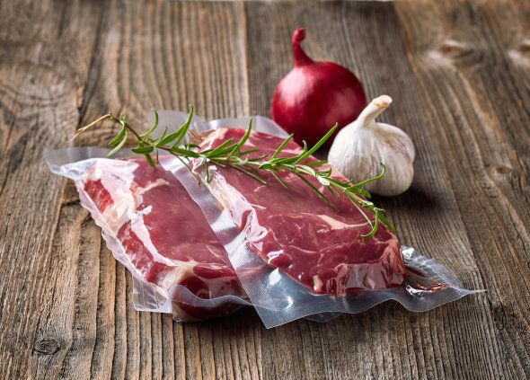 Fresh beef steak for sous vide cooking and spices on wooden table