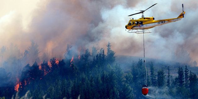 A helicopter water bombs a fire on January 21, 2016 in Cape Town, South Africa. This year wildfires again threaten the Stellenbosch area.