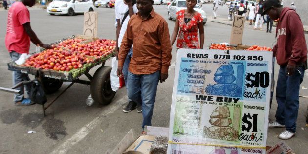 Locals walk past old currency notes on display along a street in the capital Harare, Zimbabwe, November 18, 2016. Picture taken November 18, 2016. To match Insight ZIMBABWE-MUGABE/ REUTERS/Philimon Bulawayo