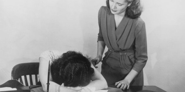 A woman moves to comfort a co-worker who is slumped over her desk in despair, circa 1940. (Photo by FPG/Hulton Archive/Getty Images)