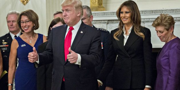 U.S. President Donald Trump, center left, gives a thumbs up next to U.S. First Lady Melania Trump, center right, during an official photograph with senior military leaders and spouses in the State Dining room of the White House in Washington, D.C., U.S., on Thursday, Oct. 5, 2017. President Trump and the First Lady are hosting the group for dinner in the Blue Room of the White House. Photographer: Andrew Harrer/Bloomberg via Getty Images