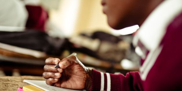 A young South African girl works on her studies at an old worn desk in a class room in the Transkei region of rural South Africa.