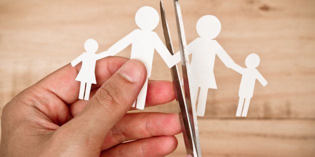 Hand with scissors cutting paper cut out with family member shape / Family problem / Divorce concept
