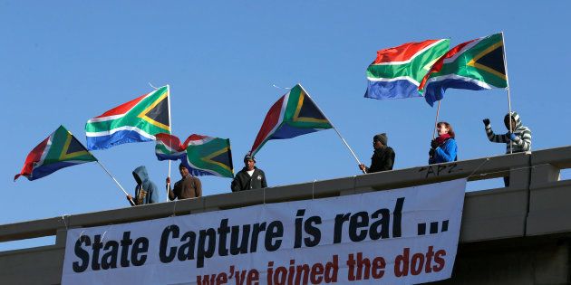 Protesters hang a banner as they hold flags in protest ahead of the African National Congress 5th National Policy Conference at the Nasrec Expo Centre in Soweto, South Africa, June 30, 2017. REUTERS/Siphiwe Sibeko