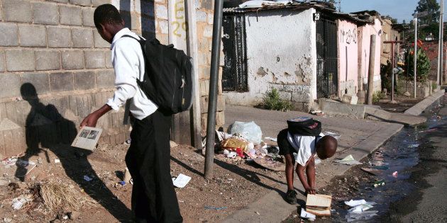 Children on their way to school in Alexandra township, Johannesburg, pick up books on the street in the running water from the blocked drain, 21 Febuary 2007.