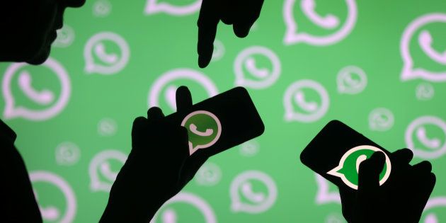 Men pose with smartphones in front of displayed Whatsapp logo in this illustration September 14, 2017.