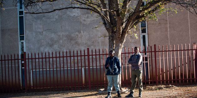 Municipal private security officials stand armed outside the Ditsobotla Municipal Offices where Mayor Daniel Buthelezi was held hostage by protesting community members in Lichtenburg on May 25, 2017. Protesters set the building on fire and threatened to set themselves alight if their service delivery complaints were not heard.