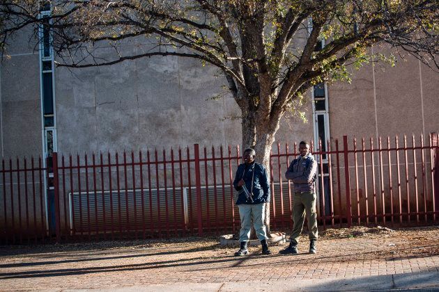 Municipal private security officials stand armed outside the Ditsobotla Municipal Offices where Mayor Daniel Buthelezi was held hostage by protesting community members in Lichtenburg