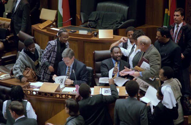 Cyril Ramaphosa (sitting R), chairperson of the Constitutional Assembly (CA), and Leon Wessels, deputy chairperson (L) and members of parliament sign copies of the amended Constitution in Parliament, on October 11, 1996, in Cape Town.