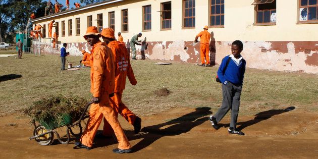 A school boy looks as he walks past prisoners who are cleaning and painting his school in Qunu, eastern cape, July 18 2012.