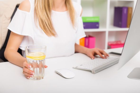 Woman drinking water while working at the office