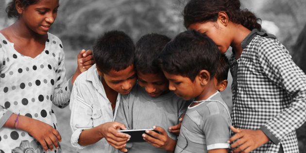 Children huddle over a smartphone.
