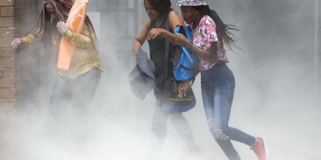 Tshwane University of Technology (TUT) students flee chemicals from a fire extinguisher during #FeesMustFall protests in October 2016 in Pretoria. TUT protesting students attempted to shut down the Pretoria CBD, clashed with police who used rubber bullets and stun grenades to disperse them.