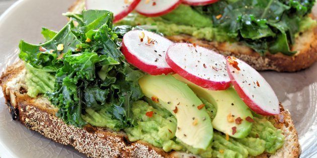 Healthy avocado toast close up with kale and radish on whole grain bread