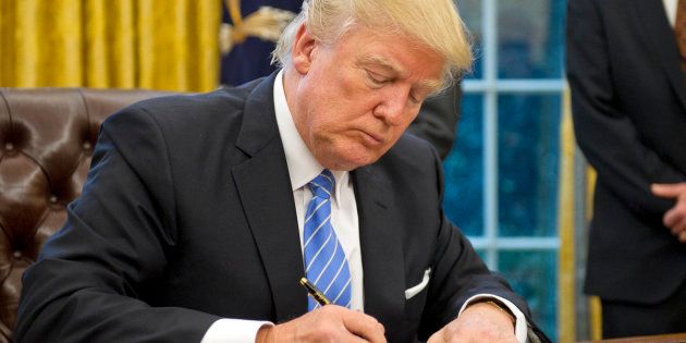 WASHINGTON, DC - JANUARY 23: (AFP OUT) U.S. President Donald Trump signs the last of three Executive Orders in the Oval Office of the White House in Washington, DC on Monday, January 23, 2017. These concerned the withdrawal of the United States from the Trans-Pacific Partnership (TPP), a US Government hiring freeze for all departments but the military, and 'Mexico City' which bans federal funding of abortions overseas. (Photo by Ron Sachs - Pool/Getty Images)