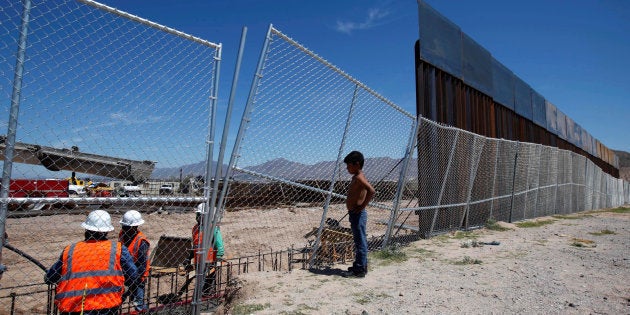 A boy looks at U.S. workers building a section of the U.S.-Mexico border wall at Sunland Park, U.S. opposite the Mexican border city of Ciudad Juarez, Mexico, in September 2016.