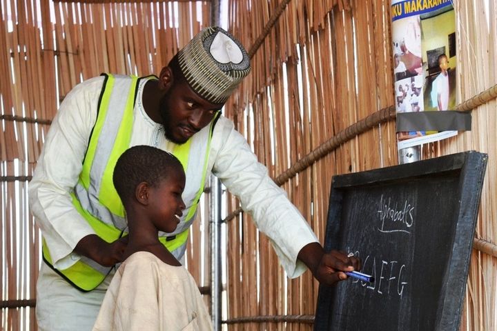 A teacher works with a young pupil in a refugee camp in Maiduguri, Nigeria, Jan 18, 2017. Thomson Reuters Foundation/Kieran Guilbert.