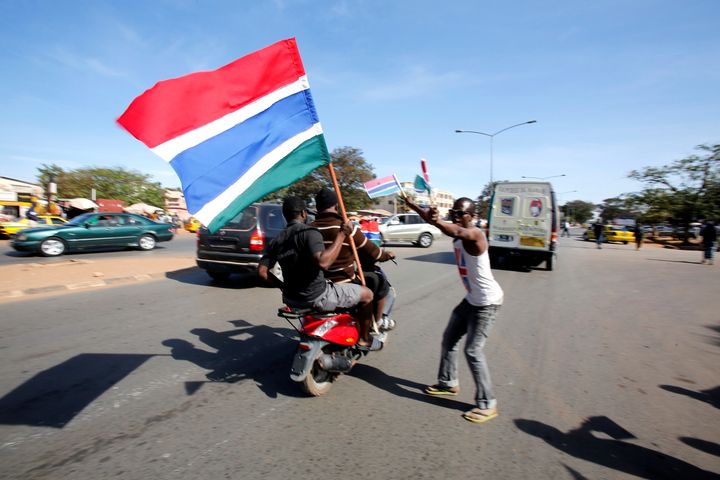 People hold Gambian flags along a street as they celebrate the slated return of Gambia's new President Adama Barrow to the country, in Serekunda, Gambia January 26, 2017.