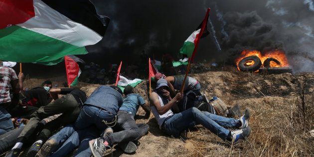 Palestinian demonstrators take cover from Israeli fire and tear gas during a protest against U.S. embassy move to Jerusalem and ahead of the 70th anniversary of Nakba, at the Israel-Gaza border in the southern Gaza Strip May 14, 2018. REUTERS/Ibraheem Abu Mustafa