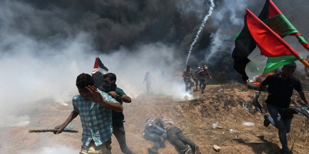 Palestinian demonstrators run for cover during a protest against U.S. embassy move to Jerusalem and ahead of the 70th anniversary of Nakba, at the Israel-Gaza border in the southern Gaza Strip May 14, 2018.