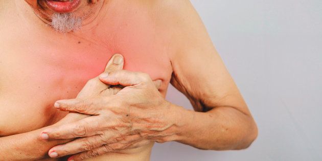 A man clutches his breast area because of pain.