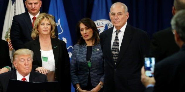 U.S. Homeland Security Secretary John Kelly (R) looks on as U.S. President Donald Trump signs an executive order at Homeland Security headquarters in Washington, U.S., January 25, 2017.