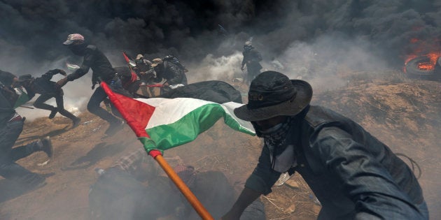 Palestinian demonstrators run for cover from Israeli fire and teargas during a protest at the Israel-Gaza border. May 14, 2018.