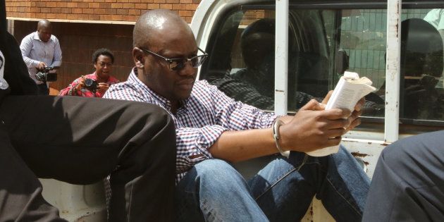 Zimbabwean pastor Evan Mawarire reads a bible, handcuffed, as he arrives at the Harare Magistrates court. (Philimon Bulawayo/Reuters)