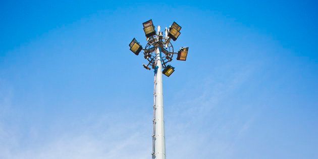 Circle of bulbs, cell phone gsm antennas on tall metal pole.