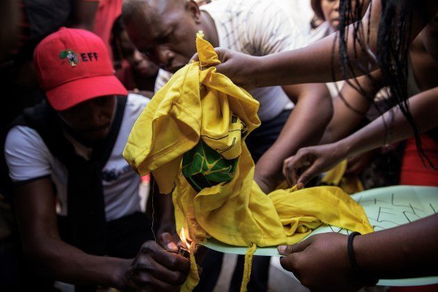 EFF members and supporters try to set fire to and tear apart an ANC T-shirt while protesting against President Jacob Zuma ahead of his State of the Nation address on February 9, 2017 in Cape Town. A violent brawl broke out in Parliament as guards exchanged punches with opposition lawmakers who shouted down Zuma as he tried to deliver his address. In chaotic scenes, about 30 guards dressed in white shirts forcibly ejected about 25 members from the radical leftist EFF who had prevented the president from speaking for about an hour.