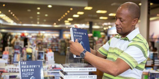 A staff member of the Exclusive Books bookshop at the Gateway Mall in Durban sets up a shelf with the new book 'The President's Keepers' written by investigative journalist and author Jacques Pauw.