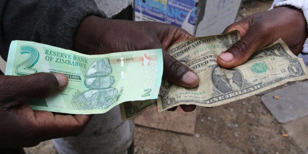 Illegal money changers pose while exchanging a new Zimbabwe bond note (L) and U.S. dollar notes in the capital Harare, Zimbabwe, November 28, 2016.