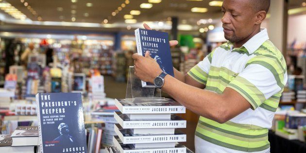 A staff member of Exclusive Books at Gateway Mall in Durban sets up a shelf of 'The President's Keepers', written by investigative journalist and author Jacques Pauw.