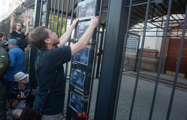 A man places the portraits of murdered journalist Arkady Babchenko on a fence of the Russian embassy in Kyiv, Ukraine. 30 May. 2018.