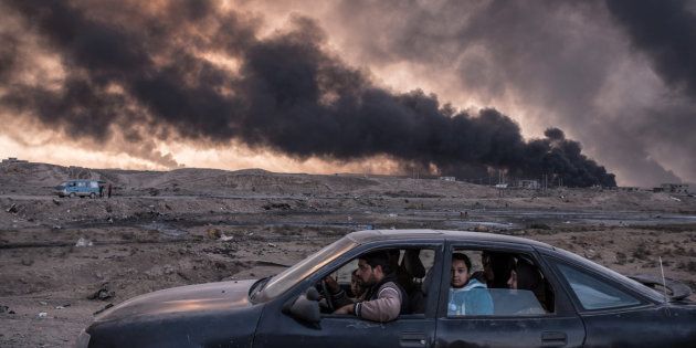 A family flees the fighting in Mosul, Iraq's second-largest city, as oil fields burned in Qayyara, Iraq, on Nov. 12, 2016. This image won second place in the General News stories category.