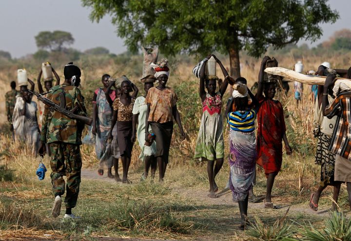 A soldier walks past women carrying their belongings near Bentiu, northern South Sudan, February 11, 2017. REUTERS/Siegfried Modola