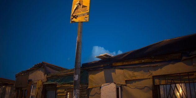 A poster with a photo of South African president, Jacob Zuma hangs over an informal settlement, close to a voting station in Langa, on election day, during the South African local government elections, on August 3, 2016, in Cape Town.