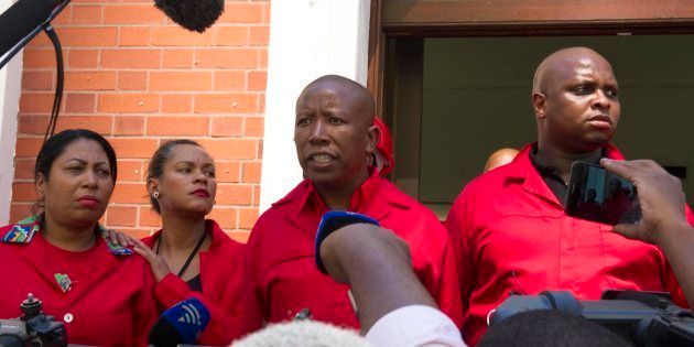 EFF leader Julius Malema (C) and fellow EFF members of Parliament answer journalists' questions as they walk out of the National Assembly on February 16 2018 in Cape Town.