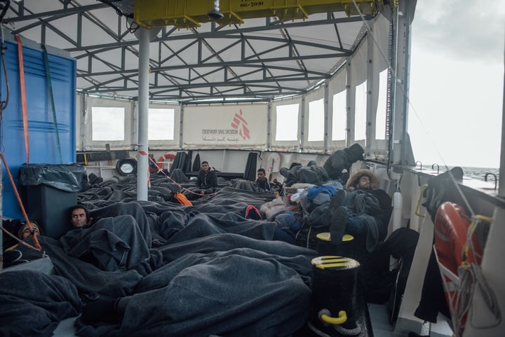 Men, women and children, rest on the deck of the MSF - SOS Mediterranee MV Aquarius after a harrowing nighttime rescue in high seas and appalling conditions in the Mediterranean sea.