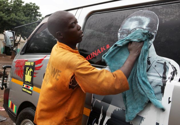 Youth washes a minibus adorned with picture of President Robert Mugabe at a bus terminus in Harare, Zimbabwe, November 15, 2017.