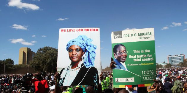 Youths from the ruling ZANU-PF party hold portraits of President Robert Mugabe and his wife Grace during the