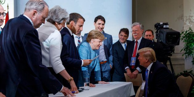 Prime Minister Justin Trudeau, British Prime Minister Theresa May, French President Emmanuel Macron, German Chancellor Angela Merkel, and U.S. President Donald Trump discuss the joint statement following a breakfast meeting at the G7 summit in La Malbaie, Que. on June 9, 2018.
