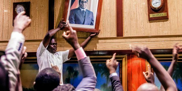 People remove, from the wall at the International Conference centre, where parliament had their sitting, the portrait of former Zimbabwean President Robert Mugabe after his resignation on November 21, 2017 in Harare.