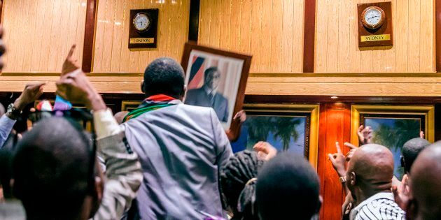 People remove, from the wall at the International Conference centre, where parliament had their sitting, the portrait of former Zimbabwean President Robert Mugabe after his resignation on November 21, 2017 in Harare.