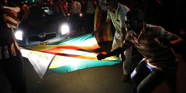 Zimbabweans celebrate with the national flag after President Robert Mugabe resigns in Harare, Zimbabwe November 21, 2017.