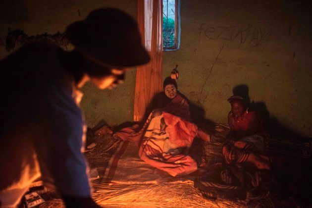 Traditional Xhosa initiates Fezikhaya Tselane (L), 20 years old, and doctor Sonwabile Madibela (R), 23 years old, rest by the fire during a traditional initiation process, in a rural hut on July 13, 2017 in the Coffee Bay area in Umtata, South Africa.