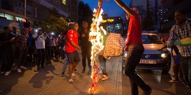 Zimbabweans living in South Africa celebrate by burning a banner with Robert Mugabe?s image after President Robert Mugabe resigns, in Johannesburg, South Africa November 21, 2017.