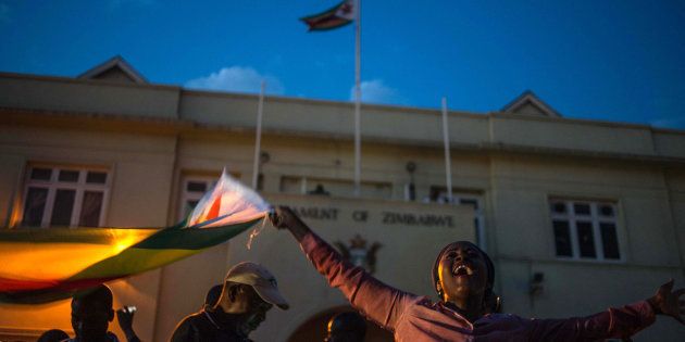 Harare residents celebrate in front of the parliament after the resignation of Zimbabwe's president Robert Mugabe on November 21, 2017.The bombshell announcement sparks scenes of wild celebration in the streets of Harare, with car horns honking and crowds dancing and cheering over the departure of the autocrat who has ruled Zimbabwe since independence. / AFP PHOTO / MUJAHID SAFODIEN